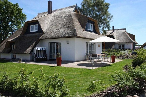 A traditional thatched-roof house with a patio area and outdoor seating. - Holiday home in Usedom with 3 bedrooms (Heringsdorf)