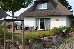 Ein Haus mit einem Strohdach, einem großen Fenster und einem Schild, das die Hausnummer 92 anzeigt.