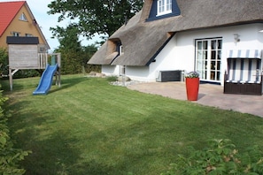 A house with a thatched roof, a blue slide, and a red planter. - Holiday home in Usedom with 3 bedrooms (Heringsdorf)