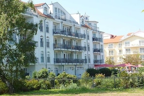 A multi-story building with balconies, a gated entrance, and a small outdoor seating area. - in the Atlantik apartment building (Kühlungsborn)