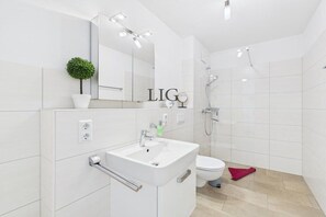 Ein modernes Badezimmer mit einem weißen Waschbecken, einem Spiegel und einer Toilette.