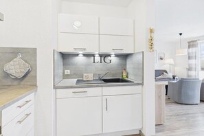 Una cocina moderna con armarios blancos, un lavamanos de acero inoxidable y una encimera.