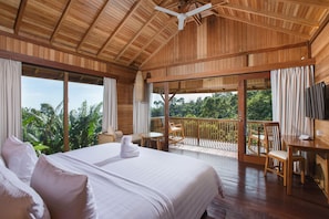 A wooden room with a bed, a balcony with a table and chairs, and a TV.
