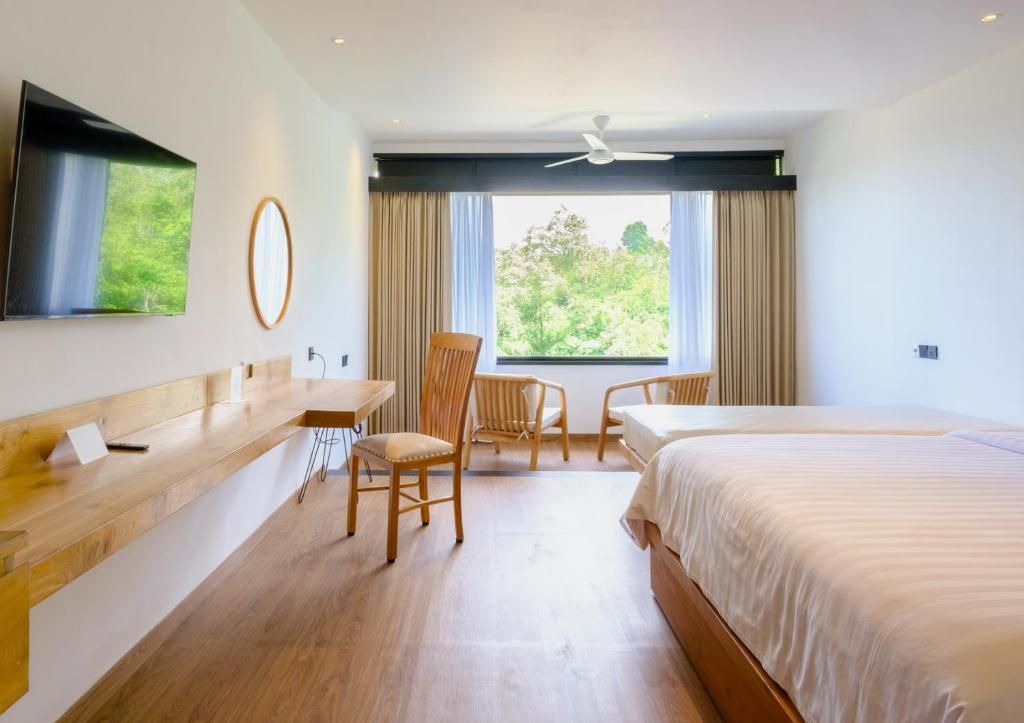 A hotel room with a bed, a desk, a chair, and a television on the wall.