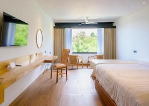 Una habitación de hotel con una cama, un escritorio, una silla y un televisor en la pared.