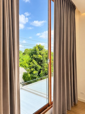 A room with a large window, curtains, and a view of greenery outside. - Spacious 3-bedroom House Near Mega Bangna and Airport (Bang Phli)