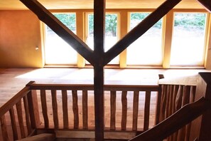 A wooden staircase leading to a balcony with a view of a landscaped area. - Shepherd's cottage Wulfsahl (Wulfsahl \/ Gusborn)