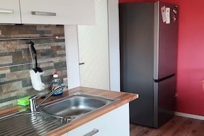 A kitchen with a stainless steel sink, a wooden countertop, a refrigerator, and a tiled backsplash. - Holiday apartment with 2 bedrooms (Bergen \/ Waldhof)