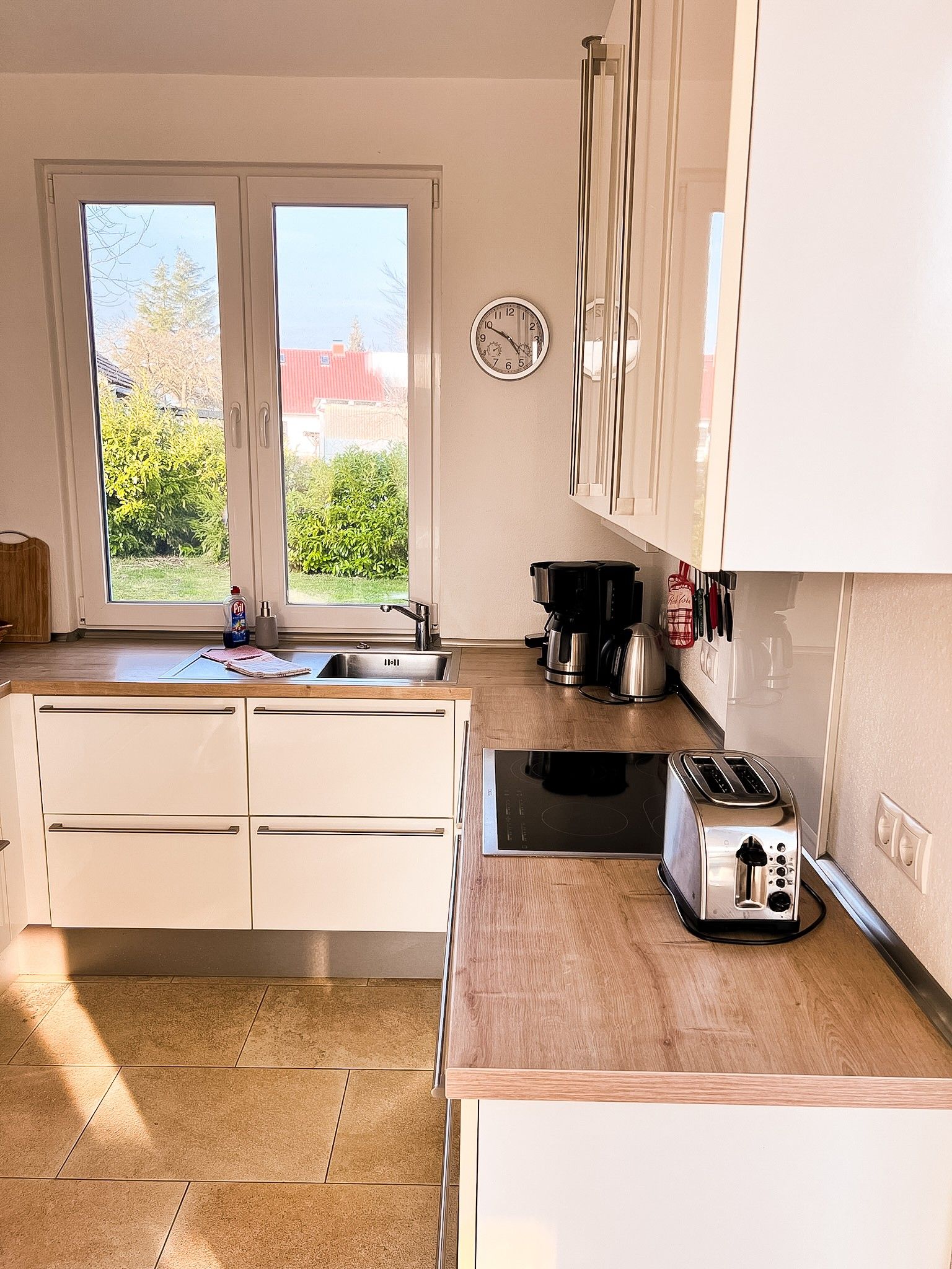 Eine Küche mit weißen Schränken, einer Edelstahlspüle, einer Kaffeemaschine und einem Toaster.