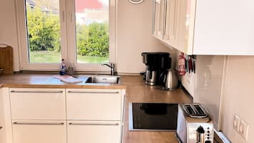 Eine Küche mit weißen Schränken, einer Edelstahlspüle, einer Kaffeemaschine und einem Toaster.