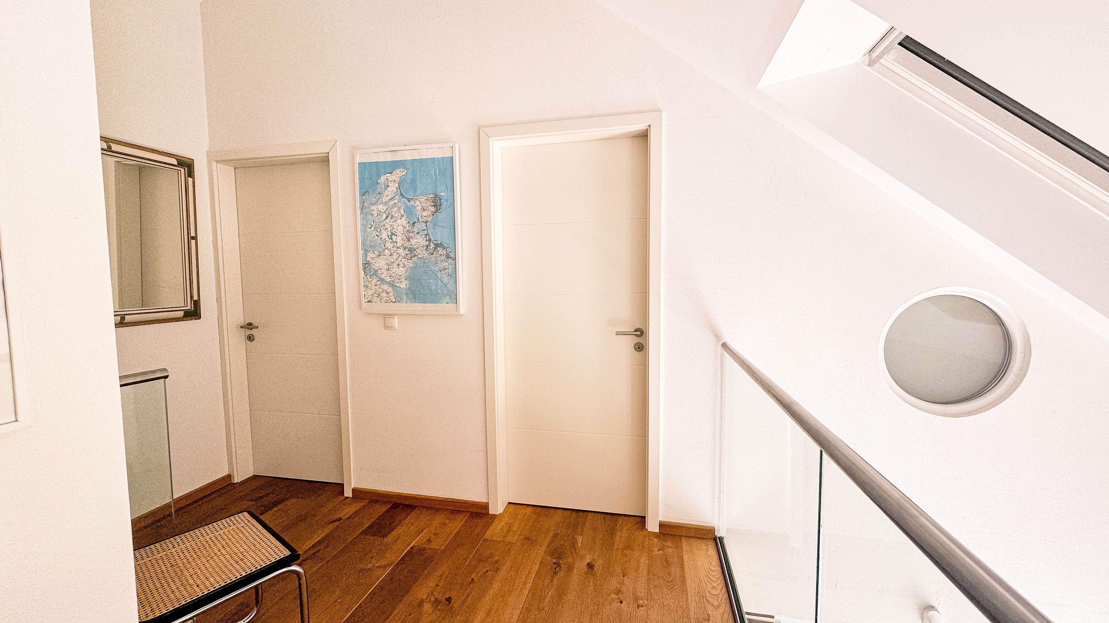 Ein Flur mit Holzboden, einer Tür mit einer Karte und einem Fenster mit einem Spiegel.