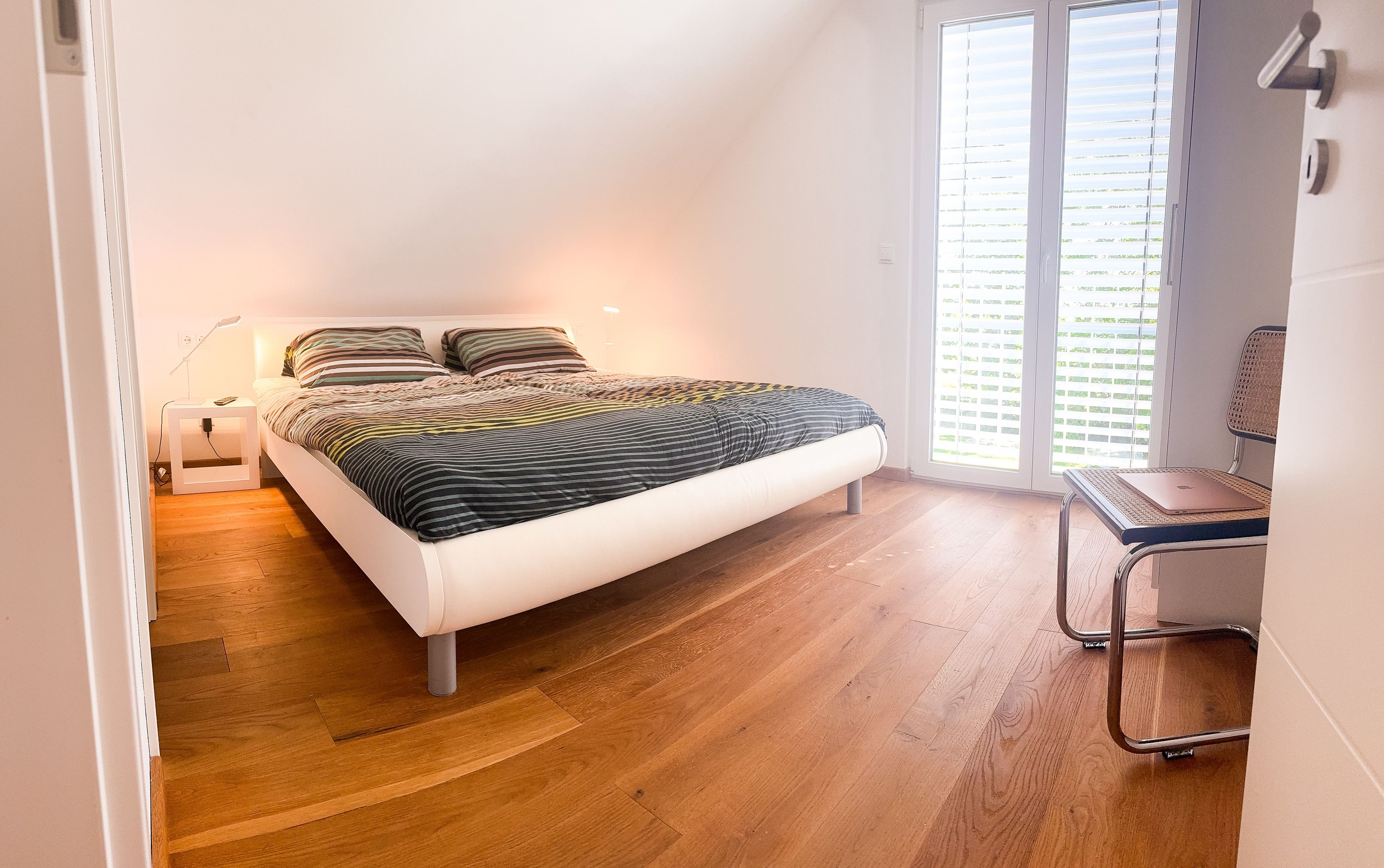 Ein Schlafzimmer mit einem Bett, einem Nachttisch, einer Lampe und einem Sessel.