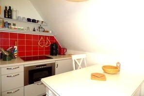 A kitchen with a red tiled backsplash, a coffee maker, and a white countertop. - Holiday apartment in Wyk with swimming pool (Wyk)