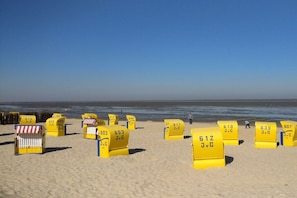 A beach with yellow lifeguard chairs labeled with numbers. - 3 in the periwinkle house (Cuxhaven-Duhnen)