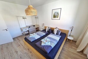Ein modernes Schlafzimmer mit einem großen Bett, Nachttischen, einem Kleiderschrank und einer Hängelampe.