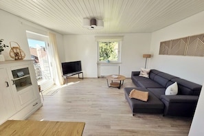 Ein modernes Wohnzimmer mit einer Couch, einem Fernseher und einem Essbereich.