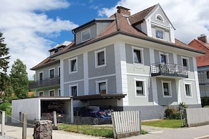 Ein zweistöckiges Wohnhaus mit Garage und Balkon, bewölkter Himmel.