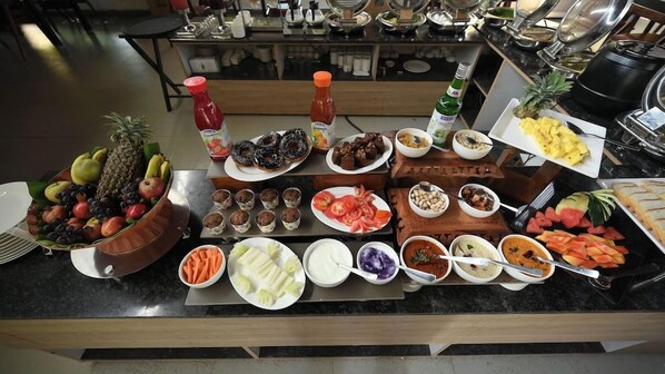 A buffet table with various food items including fruits, vegetables, and dips. - Spree One Resort and Convention (Shankhavaram)