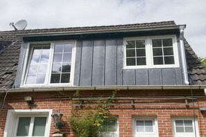 A two-story house with a satellite dish, a brick facade, and a dormer window. - Holiday apartment with 2 bedrooms (Norden)