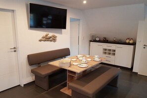 A modern kitchen with a wooden table set for tea, a bench, and a flat-screen TV mounted on the wall. - Holiday apartment with 2 bedrooms (Norden)