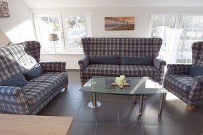 A living room with a plaid sofa set, a glass coffee table, and a painting on the wall. - Holiday apartment with 2 bedrooms (Norden)