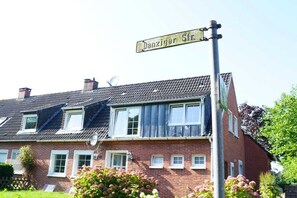 A two-story brick house with a gabled roof, a satellite dish, and a street sign reading 'Danziger Str.' - Holiday apartment with 2 bedrooms (Norden)