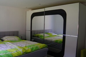 Een slaapkamer met twee bedden, een kledingkast en een spiegel.