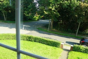 A residential street with a driveway leading to a house, surrounded by greenery and trees. - Holiday apartment with 2 bedrooms (Norden)