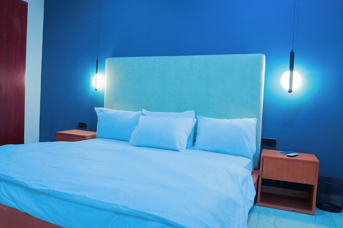 A bedroom with a bed, nightstands, and a wardrobe.
