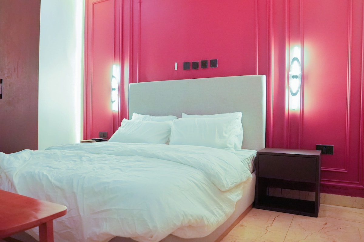 A bedroom with a bed, nightstands, a desk, and a wardrobe.