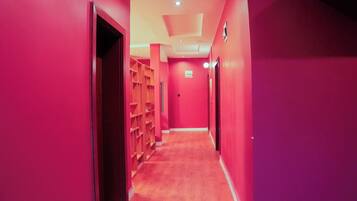 A corridor with pink walls and wooden shelving units.