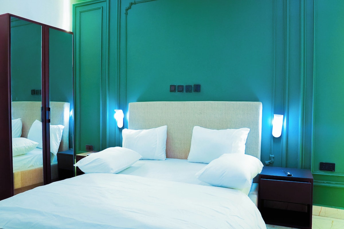 A hotel room with a large bed, two bedside tables, and a mirror.