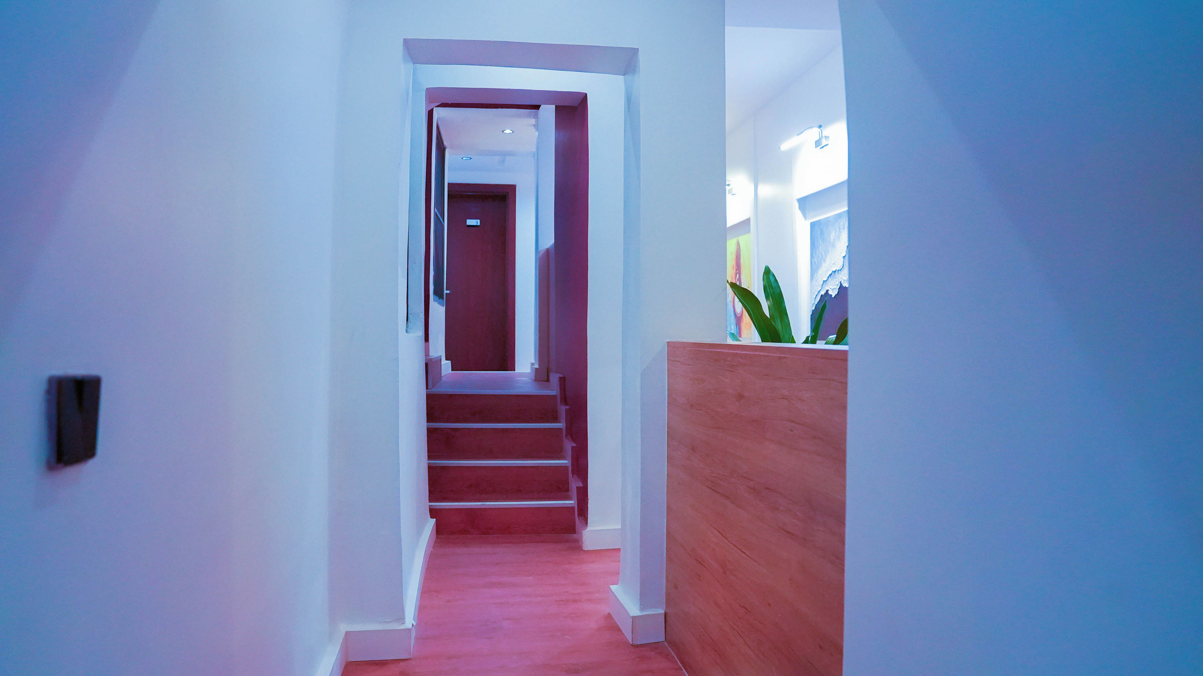 A hallway with a wooden reception desk, a staircase, and a door at the end.