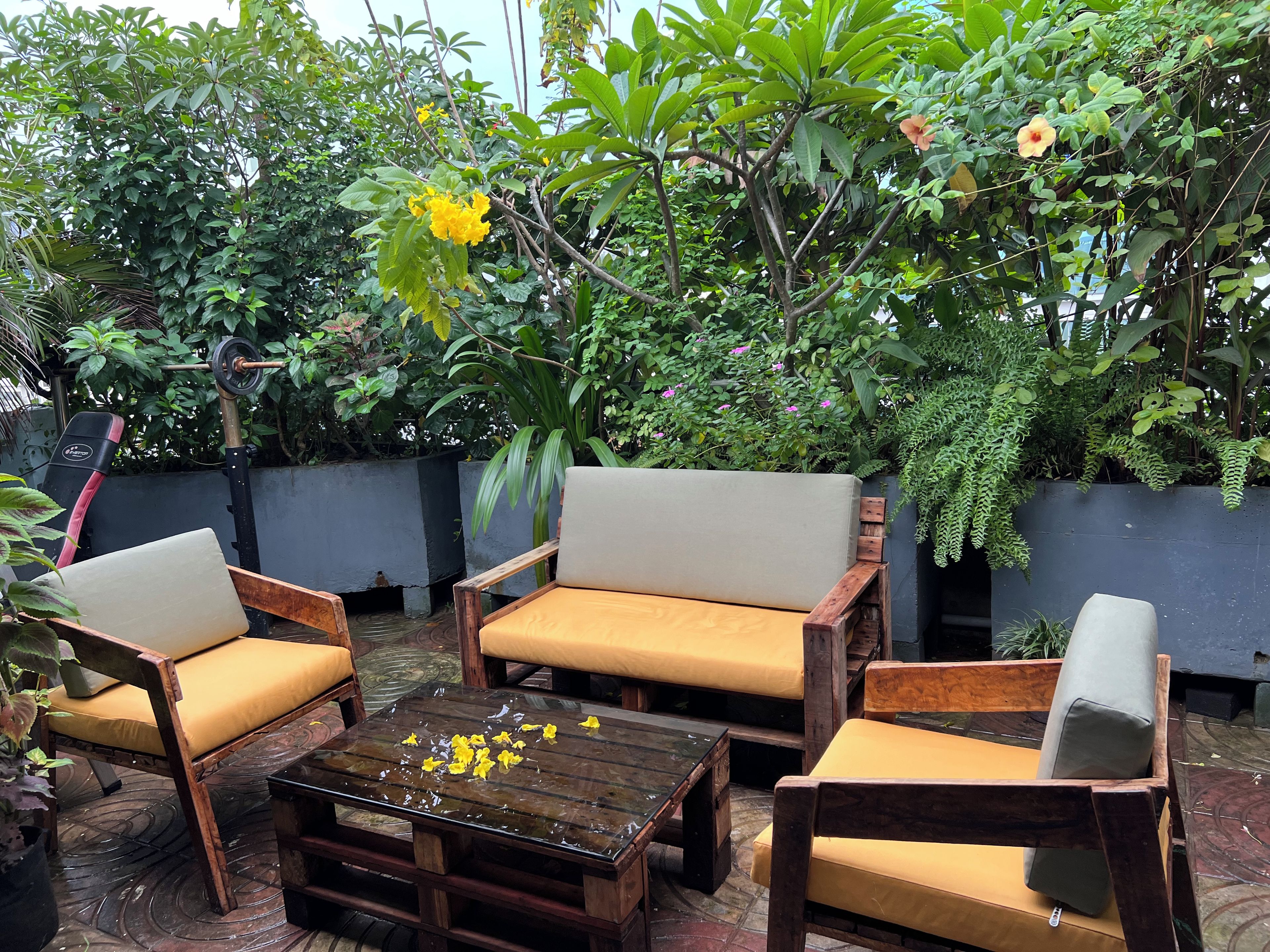 An outdoor seating area with wooden furniture and a glass coffee table.