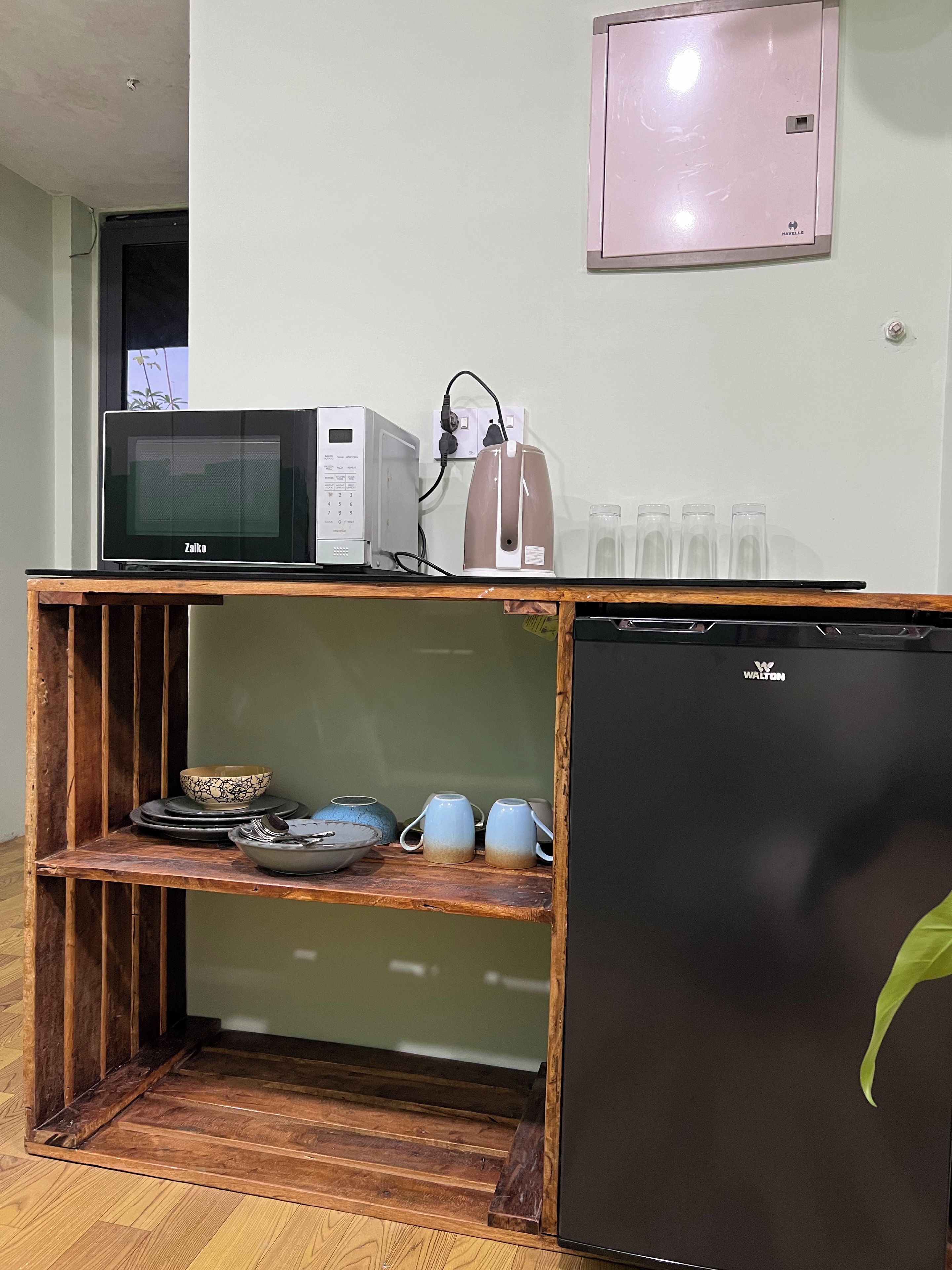A kitchenette with a microwave, kettle, and a refrigerator.