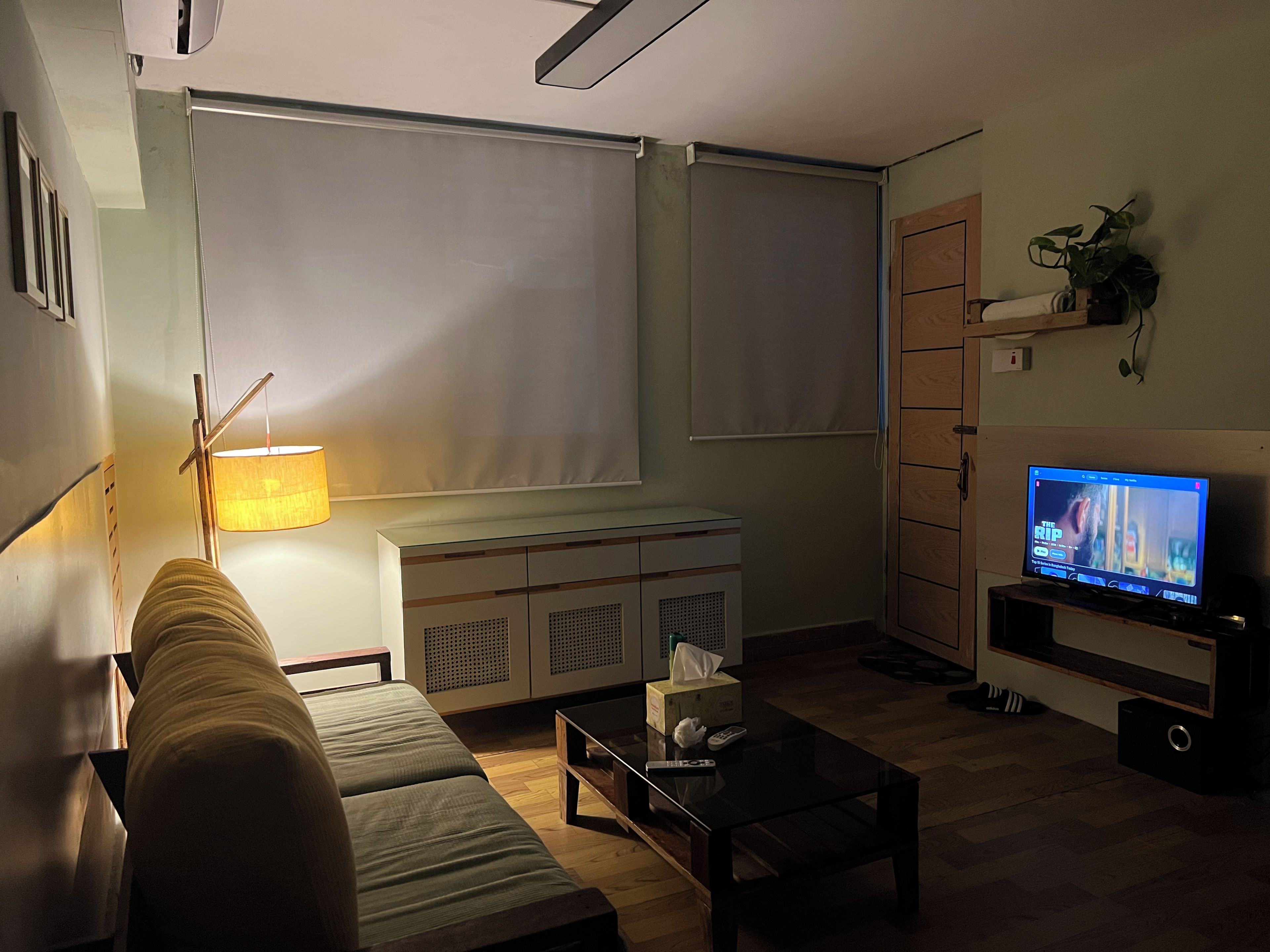 Una sala de estar con sofá, mesa de centro, televisor, lámpara y mueble.