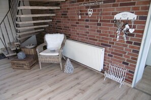 A corner room with a wicker chair, a white radiator, and a brick wall with hanging decorations. - Stork's nest Petershagen (Petershagen)