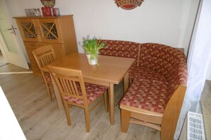 A dining area with a wooden table, two chairs, a bench, and a cabinet with glass doors. - Stork's nest Petershagen (Petershagen)