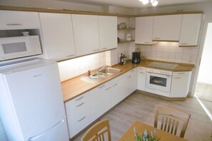 A compact kitchen with white cabinets, a microwave, a coffee maker, and a dishwasher. - Stork's nest Petershagen (Petershagen)