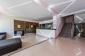 Un espace d’accueil moderne avec un mur en verre, un canapé, un comptoir et un escalier.