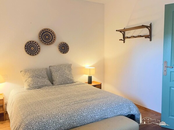 Un dormitorio con cama, lámpara de noche y tres adornos en la pared.