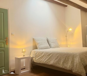 Un dormitorio con cama, lámparas de noche, una mesita de noche y una puerta verde.