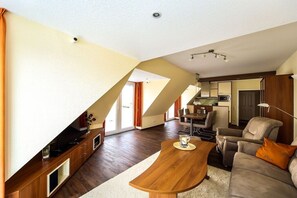 A modern living room with a wooden coffee table, a sofa, and a TV on a wooden stand. - Palace by the Sea, Apt. 7 (Cuxhaven)