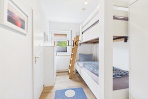 A compact room with bunk beds, a ladder, a window, and a door. - Holiday apartment Dorfschatz (Langeoog)