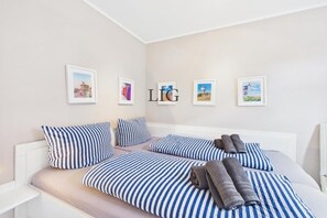 Habitación de hotel con cama, almohadas y toallas. Hay cuadros enmarcados en la pared.