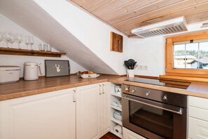 A kitchen with white cabinets, a wooden countertop, a stainless steel oven, and a window with a view of buildings. - Holiday apartment with 1 bedroom (Bad Wiessee)