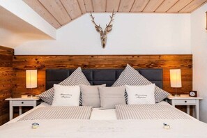 A bedroom with a wooden headboard, checkered bedding, and a mounted deer head. - Holiday apartment with 1 bedroom (Bad Wiessee)
