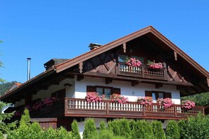 A traditional chalet with a balcony adorned with flowers, wooden balconies, and a steeply pitched roof. - Holiday apartment with 1 bedroom (Bad Wiessee)