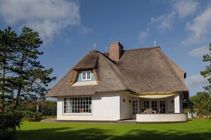 A thatched-roof house with a large window and a covered outdoor seating area. - Loddis Leev - Kampen (Sylt) (Kampen (Sylt))