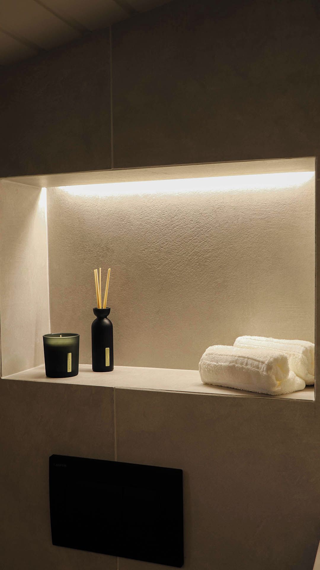Un tocador de baño con una toalla y un recipiente negro con difusores de aroma.